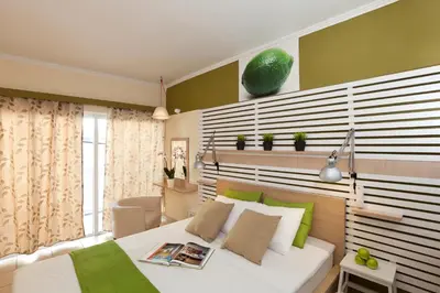 a bedroom with a large white bed with green accents at Svea Hotel in Rhodes Town
