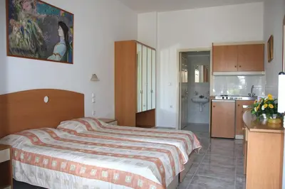 a bedroom with a large bed and a kitchen at Sun Maris in Faliraki
