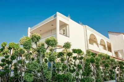 a white building with trees in front of it at Sun Maris in Faliraki