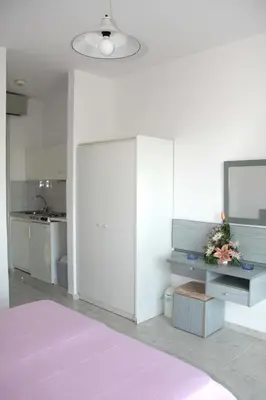 a bedroom with a purple bed and a kitchen at Sun Maris in Faliraki