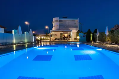 a large swimming pool in front of a building at night at Sun Maris in Faliraki