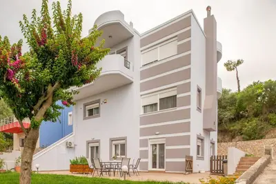 a white house with a tree in front of it at Pines Villa in Rhodes Town