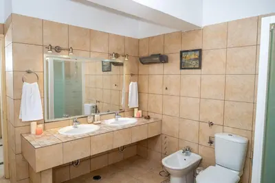 a bathroom with two sinks and a toilet and a mirror at Pines Villa in Rhodes Town