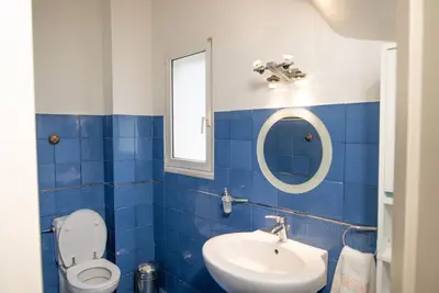 a blue tiled bathroom with a toilet and a sink at Pines Villa in Rhodes Town