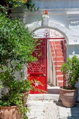 a red door on a building with plants in front at TheDreamHouse ChlorineFree Heated pool Artvillage in Koskinou