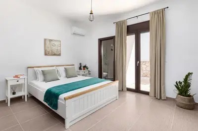 a white bedroom with a bed and a balcony at Casa Arches, Rhodes in Archipolis