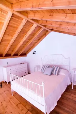 a bedroom with a white bed and a wooden ceiling at Aegli Apartments Deluxe in Symi