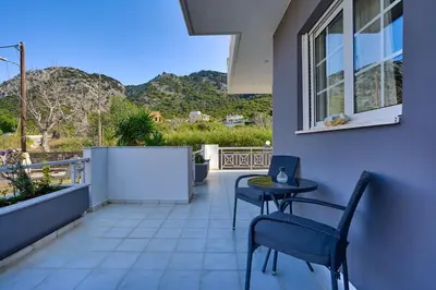 a balcony with two chairs and a table and a window at Chrysanthi Luxury Villa In Salakos, with Pool & Jacuzzi, Near Beach in Sálakos