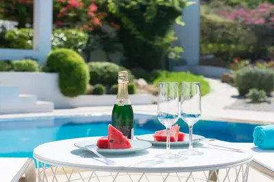 a table with a bottle of champagne and two glasses at Villa Sunshine very close to the beach in Líndos