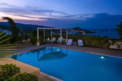 a swimming pool with a view of the ocean at night at Villa Sunshine very close to the beach in Líndos