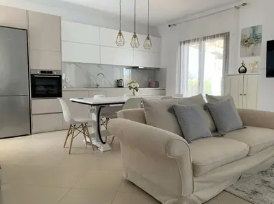 a white living room with a couch and a kitchen at Villa Sunshine very close to the beach in Líndos