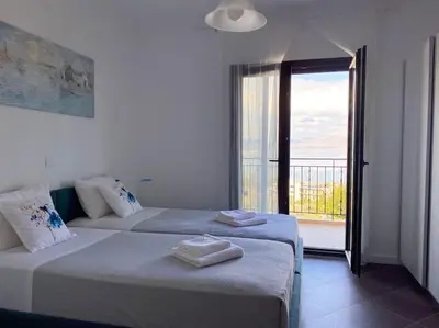 two beds in a white room with a balcony at Villa Sunshine very close to the beach in Líndos