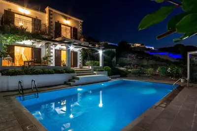 a swimming pool in front of a house at night at Villa Sunshine very close to the beach in Líndos