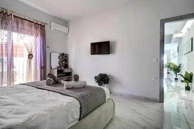 a white bedroom with a large bed and a tv at Sea & Joy House in Ialyssos