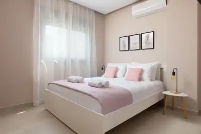 a white bedroom with a large bed with pink pillows at Ixian Memory in Triánta