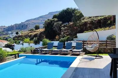 a swimming pool with chairs and a view of a mountain at Sea View Villa Ellada, Just 3km From Lindos in Líndos