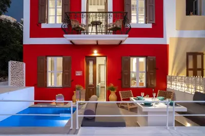 a red building with a pool in front of it at Annikas Port View-Ground in Symi