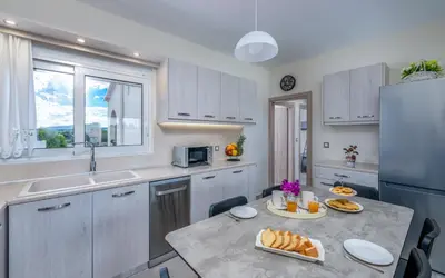 a kitchen with white cabinets and a table with food on it at Nimarevi Apartment in Soroni
