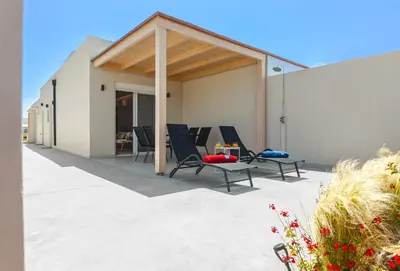a patio with chairs and a table and a building at Lago Beach Living in Faliraki
