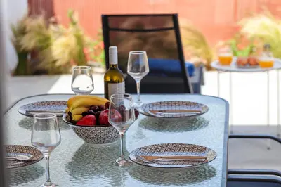 a table with glasses and a bowl of fruit and a bottle of wine at Lago Beach Living in Faliraki