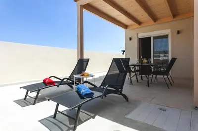 a patio with chairs and a table on a patio at Lago Beach Living in Faliraki