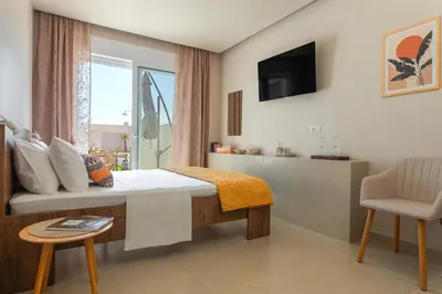 a bedroom with a bed and a window and a chair at Lago Beach Living in Faliraki