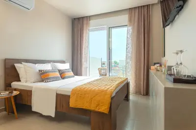 a bedroom with a bed and a large window at Lago Beach Living in Faliraki