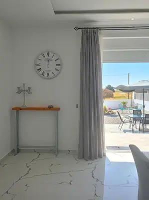a room with a clock on the wall and a table at Blue Sky Villa in Kalithies
