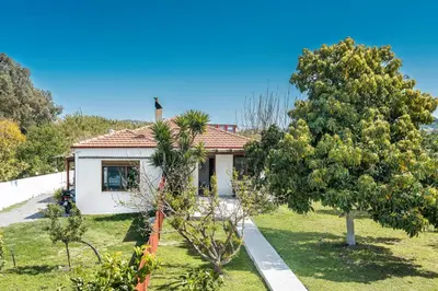 a small white house with trees in front of it at Ily’s House in Pastida