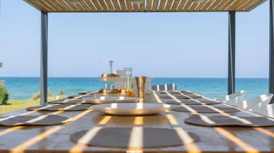 a table with chairs and the ocean in the background at Liam Beach Front Luxury Villa with 100m2 infinity pool in Phanaes