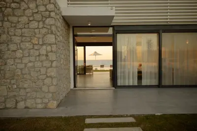 a building with glass doors with a view of the ocean at Liam Beach Front Luxury Villa with 100m2 infinity pool in Phanaes