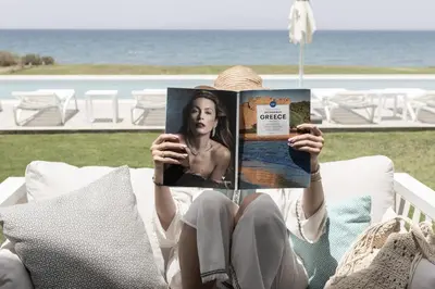 a woman sitting on a chair reading a magazine at Miguel Luxury Beach Front Villa in Phanaes