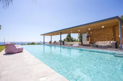 a swimming pool with chairs and a pavilion at RLM Prime Beach Panoramic Villa in Kolimbia