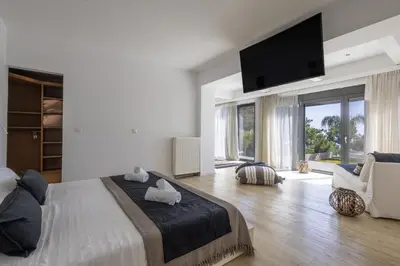 a bedroom with a large bed and a flat screen tv at RLM Prime Beach Panoramic Villa in Kolimbia