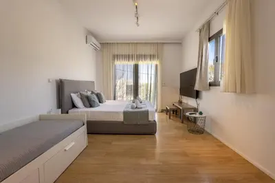 a bedroom with a bed and a desk and a window at RLM Prime Beach Panoramic Villa in Kolimbia
