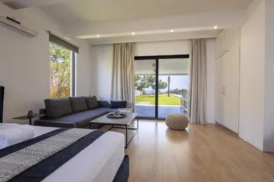 a bedroom with a bed and a couch and a table at RLM Prime Beach Panoramic Villa in Kolimbia