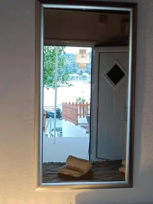 a mirror in a room with a door and a porch at Spot on the sea in Archangelos