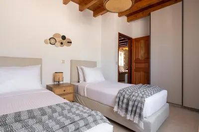 two beds in a bedroom with white walls at Villa Roi in Kalathos