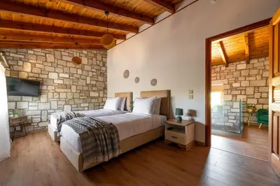 a bedroom with a bed and a stone wall at Villa Roi in Kalathos