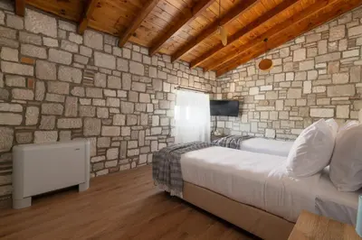 a bedroom with two beds and a stone wall at Villa Roi in Kalathos