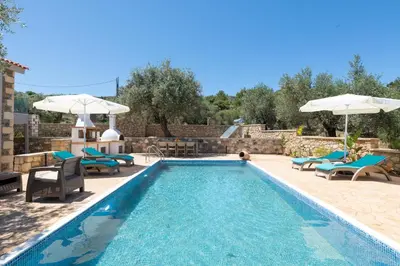 a swimming pool with chairs and umbrellas next to at Villa Roi in Kalathos