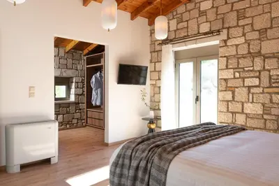 a bedroom with a bed and a stone wall at Villa Roi in Kalathos