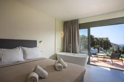 a hotel room with a bed and a tub and a balcony at Eden's Azalea Luxury Suite in Rhodes Town