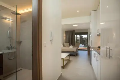 a bathroom with a walk in shower and a living room at Eden's Azalea Luxury Suite in Rhodes Town