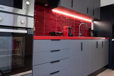 a kitchen with white cabinets and red tiles at Calliope's Rhodes City Comfort in Rhodes Town