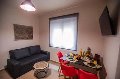 a living room with a couch and a table with red chairs at Calliope's Rhodes City Comfort in Rhodes Town