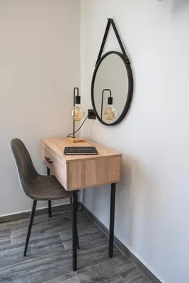 a desk with a chair and a mirror on a wall at Calliope's Rhodes City Comfort in Rhodes Town