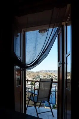 a chair sitting on a balcony looking out a window at Aeneo Studio 2 in Symi