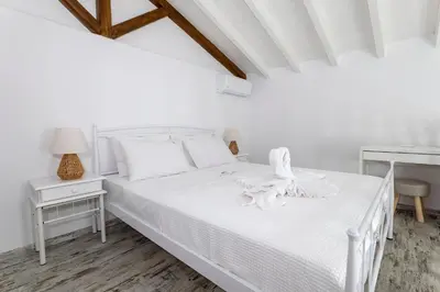 a white bedroom with a white bed and a table at Villa del Capo Suites in Rhodes Town