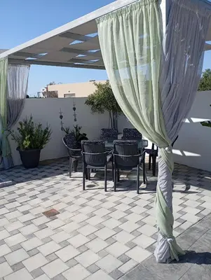 a curtain on a patio with chairs and a table at Traounou Bay villa in Afantou